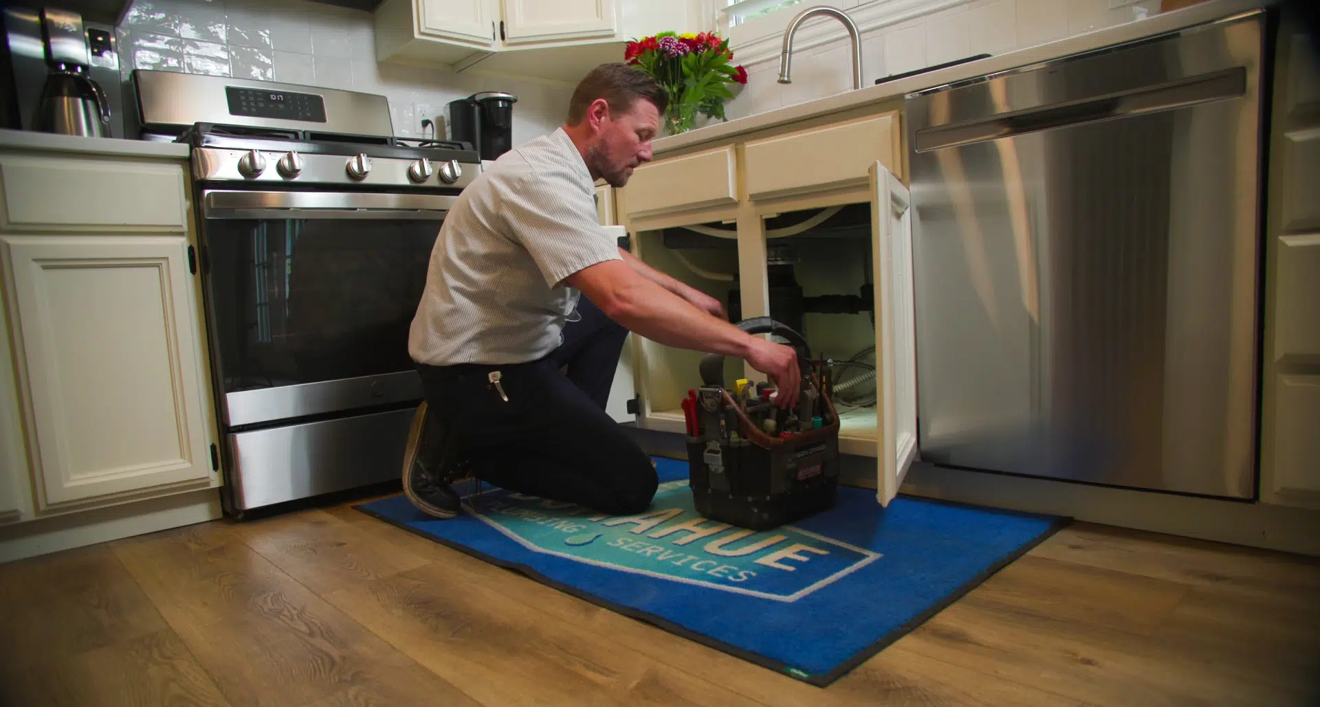 Donahue Plumbing Technician Working Under a Kitchen Sink